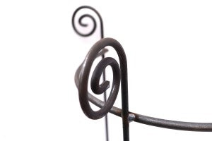 Nahaufnahme des Hirsch Staudenhalters/Rankhilfe HUGO Halbrunds mit dekorativem Spiralende vor weißem Hintergrund; eine weitere Spirale erscheint unscharf. Maße: Tiefe 22 cm, H90 cm, B45 cm.
