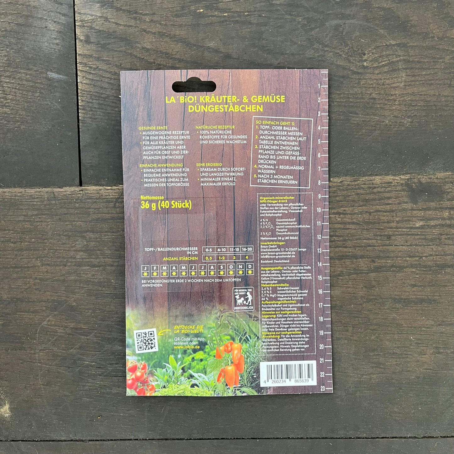 Rückseite einer La'Bio-Düngestäbchen-Packung von La'Bio mit deutschem Text, Anleitung, Barcode, QR-Code, Dosierungstabellen und einem Foto von Gemüse und Blumen mit der Betonung wichtiger Nährstoffe auf Holz. Ideal für Pflanzenliebhaber.