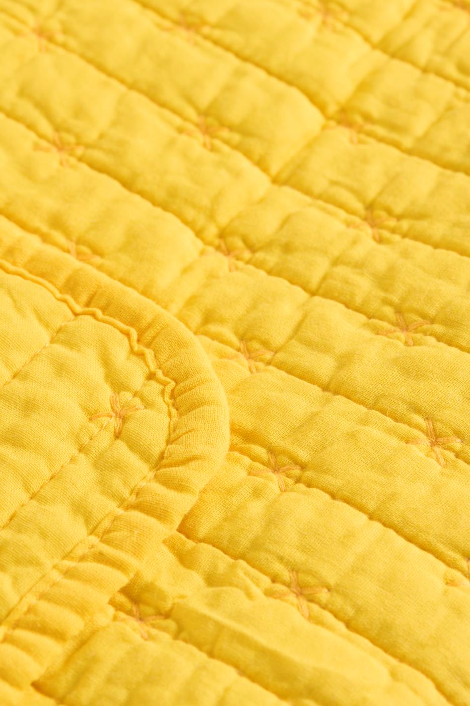 Nahaufnahme der Ib Laursen | Gelbe Tagesdecke mit Kreuzstich von IB Laursen, mit leuchtend gelber Farbe, gitterartiger Kreuzstichstruktur und sanft geschwungenem Stepprand.