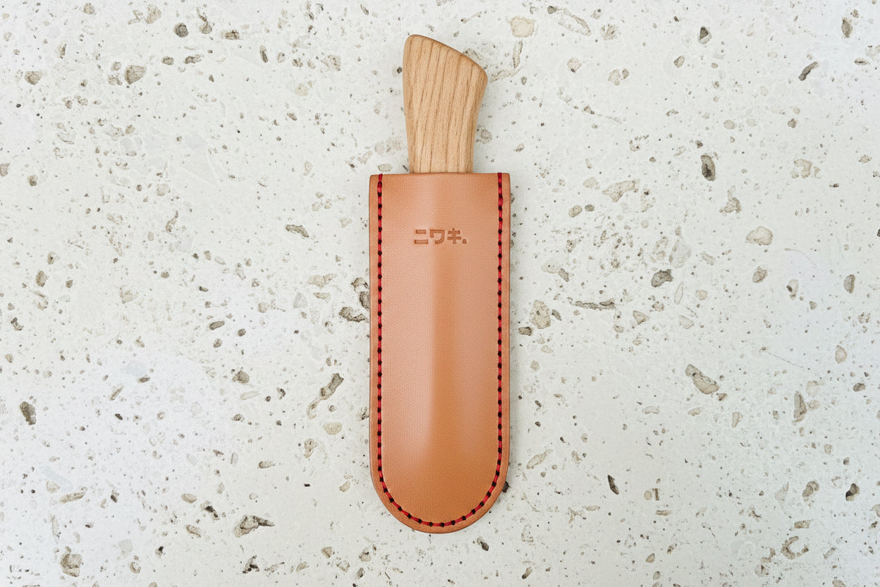 Die Niwaki | 'Leather Sheath' Lederschutzhülle für kleine Messer zeichnet sich durch hellbraunes Leder, rote Nähte und geprägte japanische Schriftzeichen im oberen Bereich aus - funktionell und stilvoll von Niwaki.