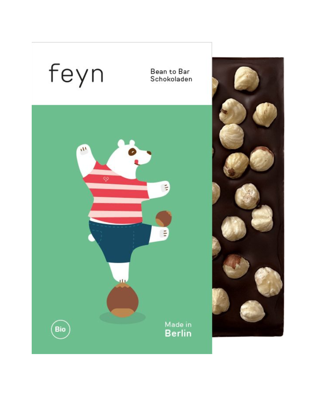 Eine Feyn-Schokoladentafel mit ganzen Bio-Haselnüssen ist teilweise in eine farbenfrohe Verpackung mit einem Cartoon-Bären in einem rot gestreiften Hemd eingewickelt. Der Text lautet "Feyn | Dunkle Schokolade mit Haselnuss" und "Made in Berlin".