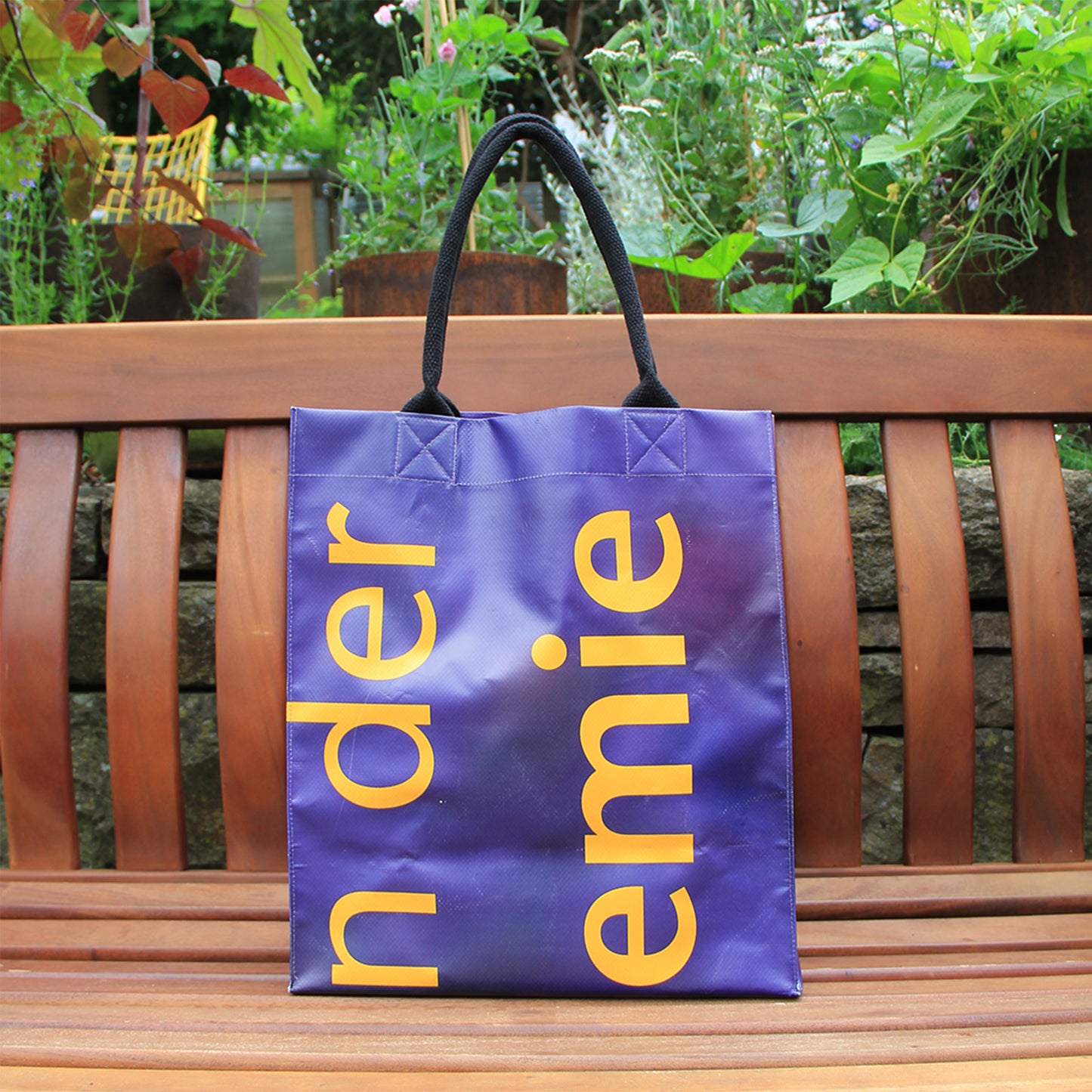 Der Upcycling KGA Shopper 'Herbs' von Königliche Gartenakademie ist eine einzigartige lila Tasche aus Werbebanner mit gelben Buchstaben und schwarzen Henkeln - ein nachhaltiges Unikat, ideal für Stadt und Natur.