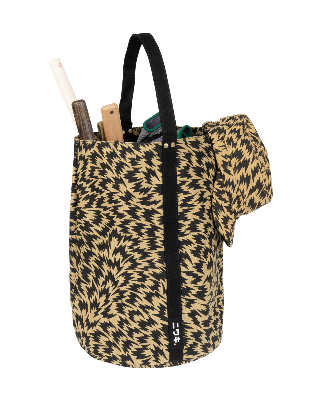 Die Niwaki Kantan Werkzeugtasche 'Eley Kishimoto X Niwaki Flash' zeichnet sich durch ein auffälliges schwarz-hellbraunes Zickzack-Muster aus. Sie fasst gerolltes Papier, hölzerne Objekte und ein Werkzeug mit grünem Griff, und an der Seite hängt eine passende Tasche.
