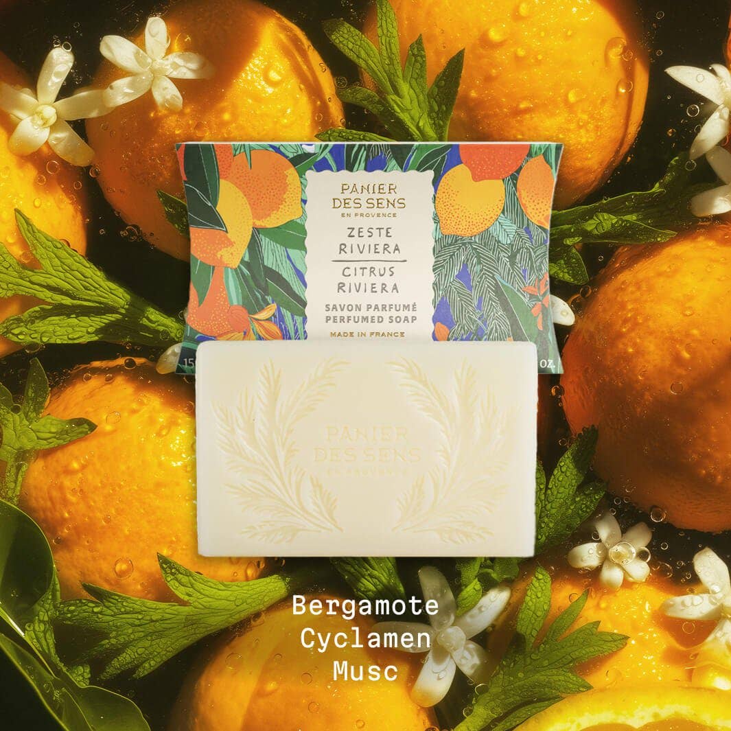 Ein Riegel Panier Des Sens | Duftseife Zeste Riviera 150 g ruht in seiner illustrierten Schachtel, umgeben von Orangen, Orangenblüten und Blättern. Der Duft von Zitrusfrüchten und Olivenöl bringt mediterrane Frische. "Bergamote Cyclamen Musc" ist unten abgebildet.