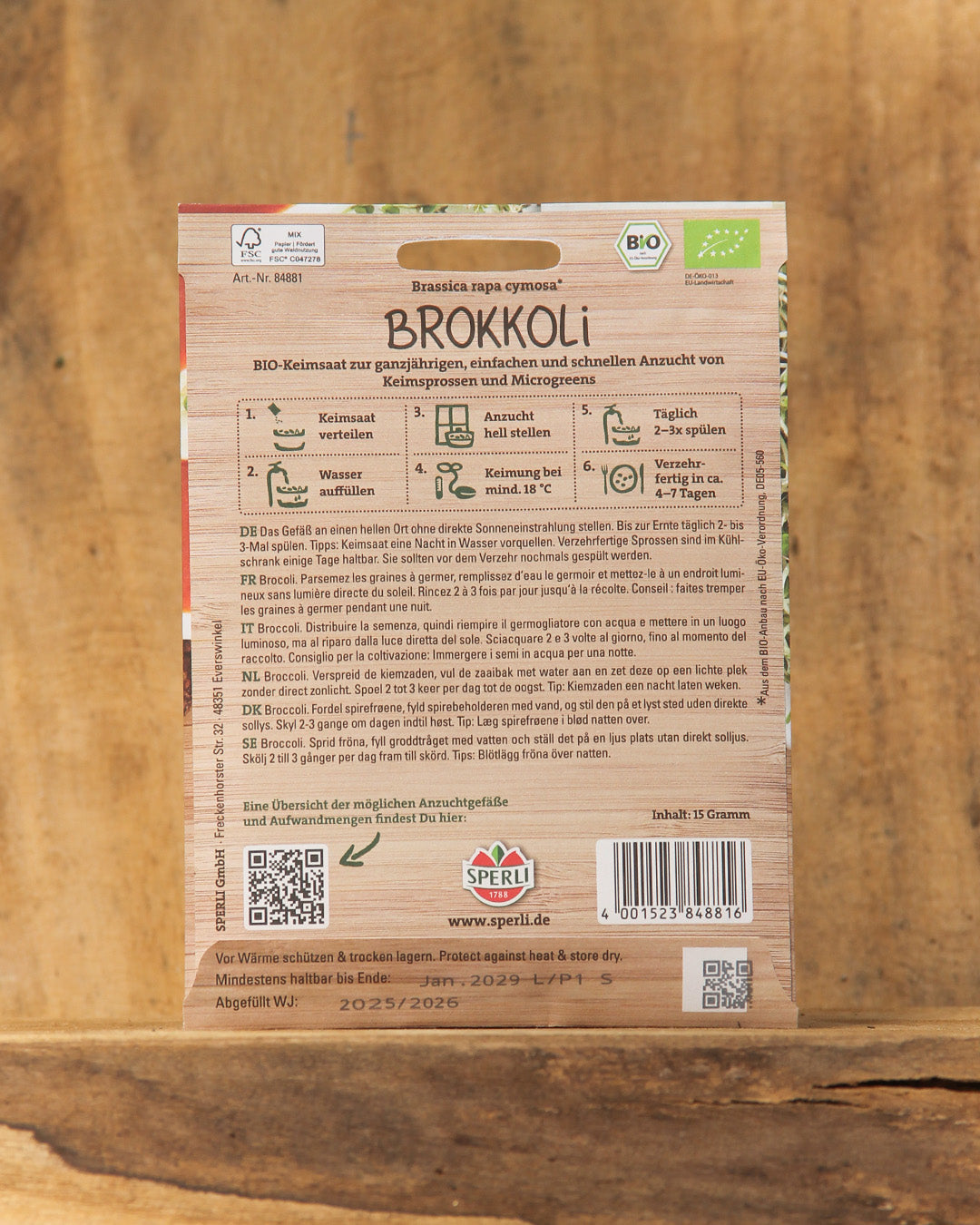 Packung Sperli's | Bio Keimsprossen Saatgut 'Brokkoli' von Sperli's, mit deutscher Pflanzanleitung und QR-Codes auf einem Holzuntergrund - ideal für selbstgezogene Keimsprossen.
