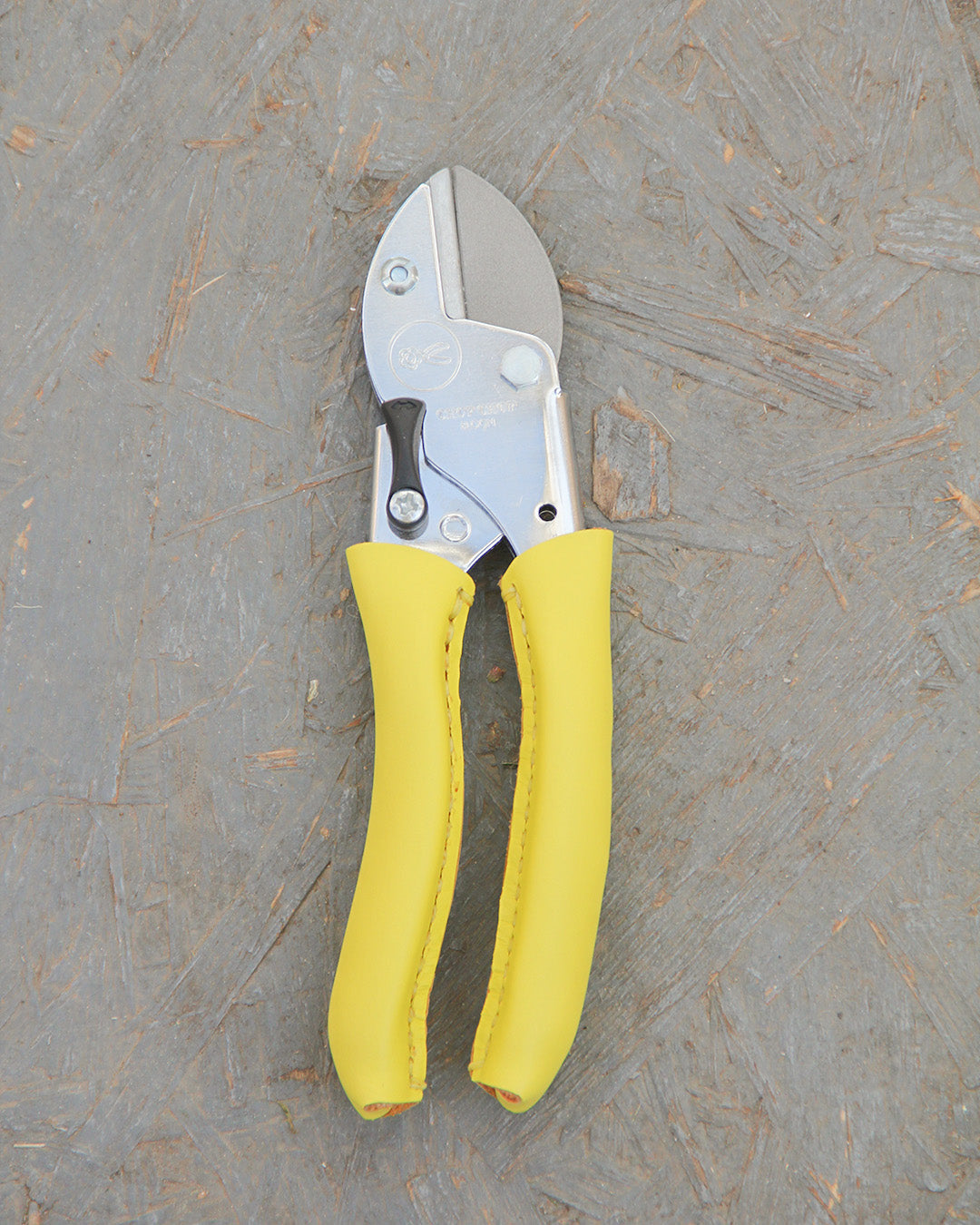 Die Chop Chop | Hochwertige Gartenschere 'Busy Lizzy' von Chop Chop Bloom, mit leuchtend gelben Griffen, ruht auf einer strukturierten grauen Oberfläche - perfekt für Ihre nächste Gartenarbeit.