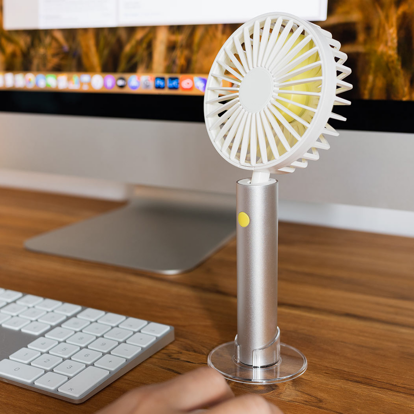 Der Remember Ventilator 'Silver' von Remember mit silbernem Griff und weißen Lamellen steht auf dem Schreibtisch in der Nähe von Computermonitor und Tastatur.