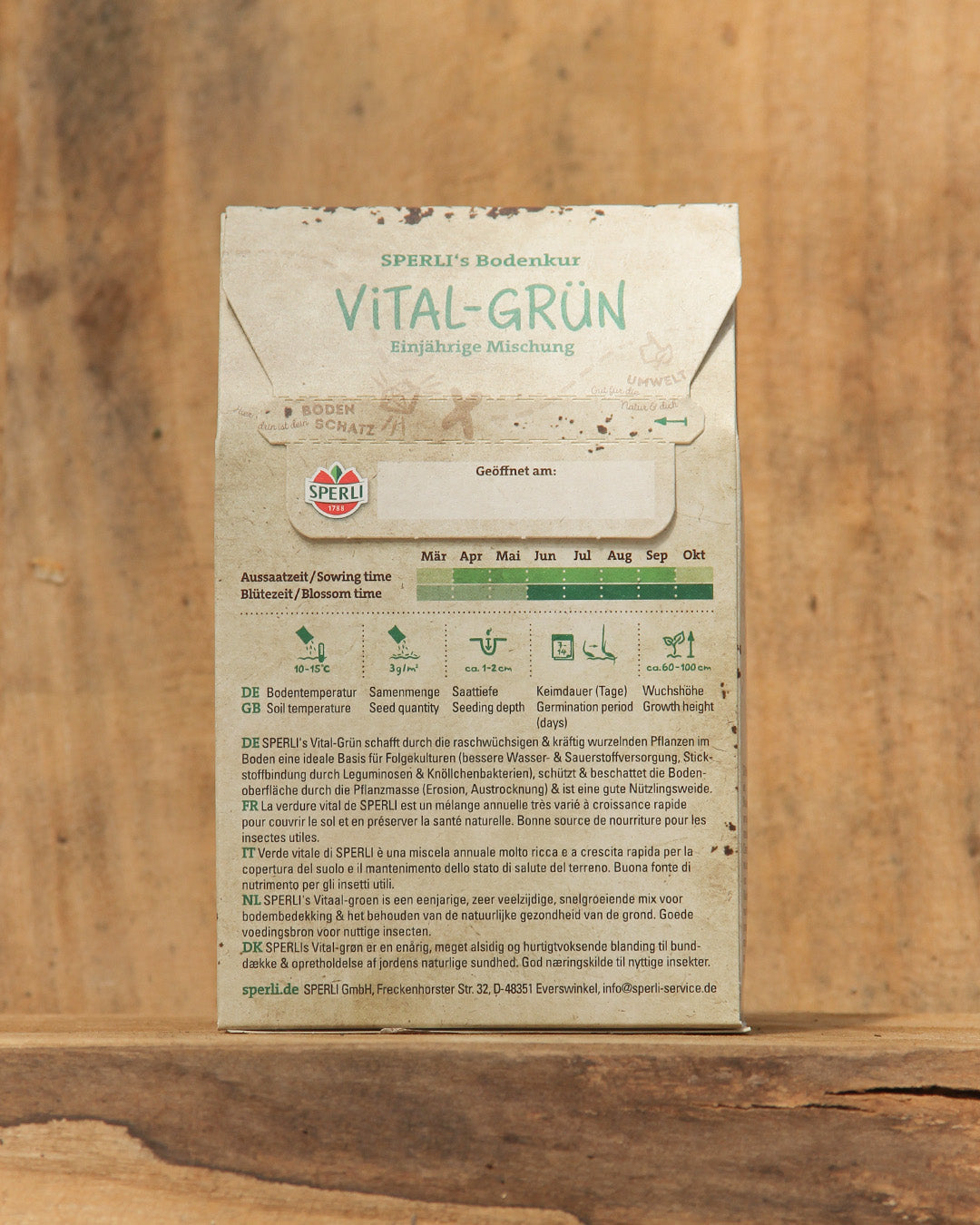 Eine 450 g-Packung der Sperli's | Gründüngermischung Bodenkur 'Vital-Grün' steht aufrecht auf Holz und trägt ein rustikales Etikett mit Pflanzangaben, Symbolen und deutscher Anleitung - ideal für die natürliche Bodenverbesserung im Garten.