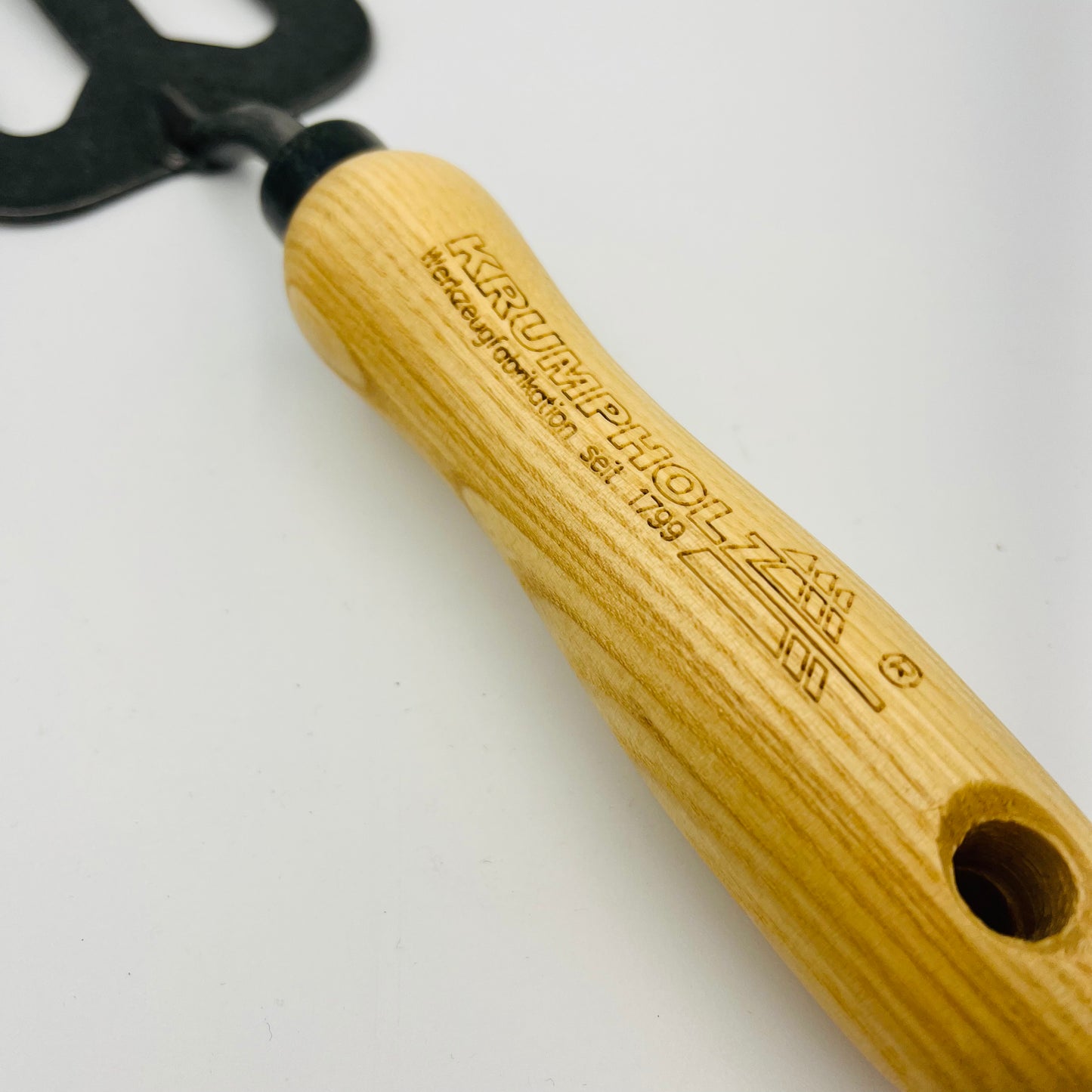 Nahaufnahme der Krumpholz | Handgabel 3-zinkig 1485, mit einem Holzgriff mit Krumpholz-Gravur und einem Aufhängeloch, ideal zum Entfernen von Unkraut, vor weißem Hintergrund.