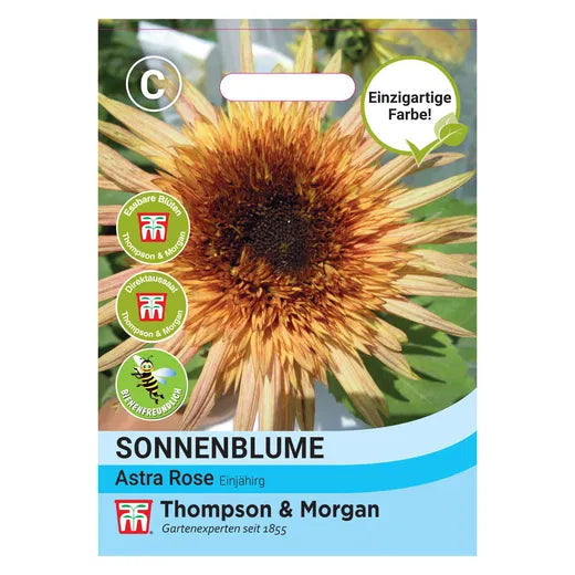 Eine Samenpackung für Thompson und Morgan | Sonnenblume 'Astra Rose' zeigt halbgefüllte Blüten mit einzigartigen rosafarbenen Blütenblättern, wie in der Nahaufnahme zu sehen. Der deutsche Text hebt die charakteristische Farbe dieser Blume hervor.