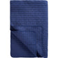 Eine ordentlich gefaltete Ib Laursen | Quilt Decke Indigo blau mit Kreuzstich von IB Laursen in marineblau zeigt eine umgedrehte Ecke, die die Unterseite und das Kreuzstich-Gittermuster zeigt.