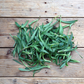 Ein Haufen frischer, grüner Blätter ruht auf rustikalem Holz - die ideale Inspiration für den Anbau eigener gentechnikfreier Kräuter auf dem Balkon mit der Piccolo Seeds | Wildkräuter Kollektion "Foraging Wild Herbs" von Piccolo Seeds.