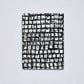 Ein nuuna | „Sassy Squares“ Notizbuch Not Ordinary L Light A5+ mit einem schwarz-weißen Einband, auf dem ein Raster aus groben, unregelmäßigen Quadraten ein abstraktes, handgezeichnetes Muster auf einem schlichten, hellen Hintergrund bildet.
