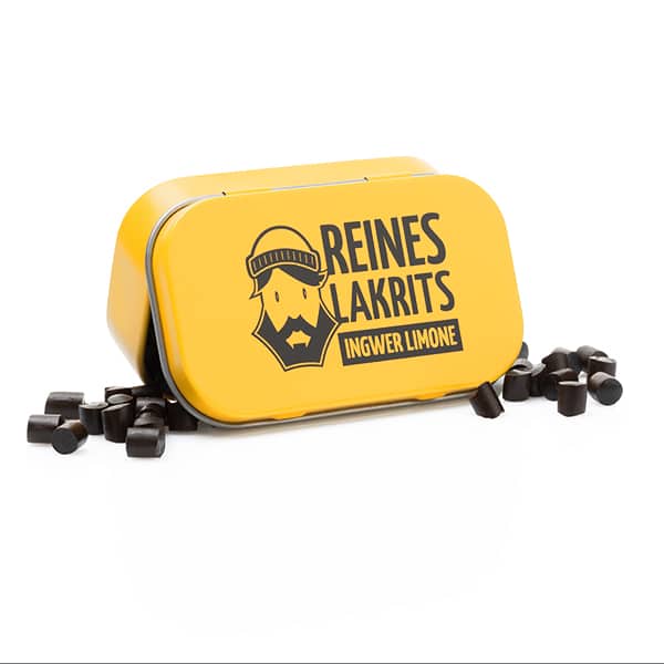 Auf einer leuchtend gelben LASSE LAKRITS-Dose mit der Aufschrift "Dose Reines Lakritz Ingwer Limone" ist ein bärtiger Mann abgebildet, um den herum natürliches Lakritz-Bonbon verstreut ist.