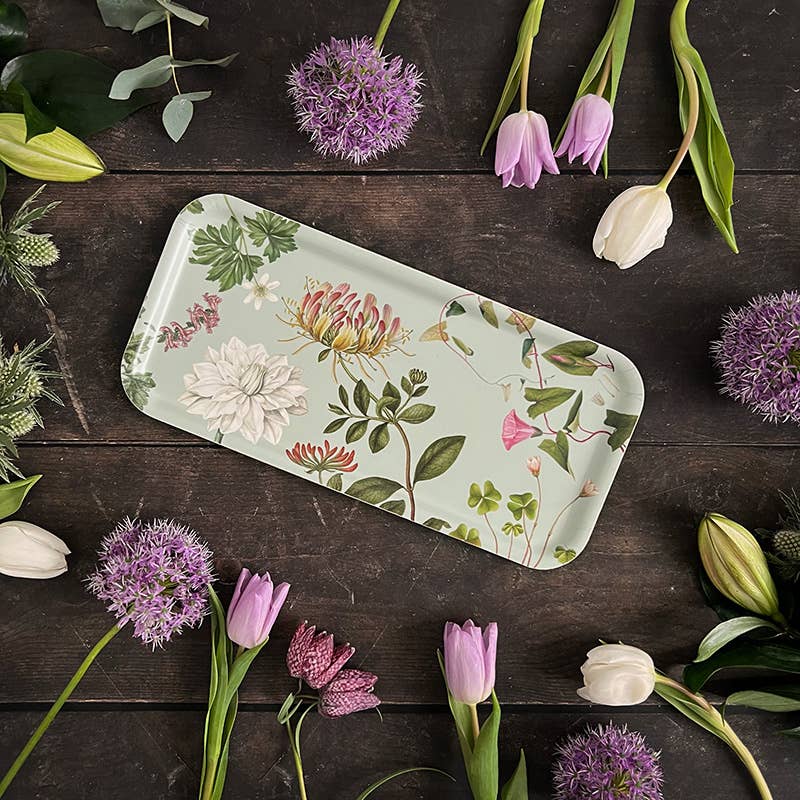 Ein Koustrupco | „Flora Danica Atlas“-Serviertablett (32 × 15 cm) aus FSC-zertifiziertem Birkenfurnier steht auf einer dunklen Holzunterlage, verziert mit arrangierten Alliumblüten, rosa Tulpen und frischem Grün. Das Tablett von Koustrupco bringt mit seinen botanischen Illustrationen einen Hauch von Natur in jedes Zuhause.