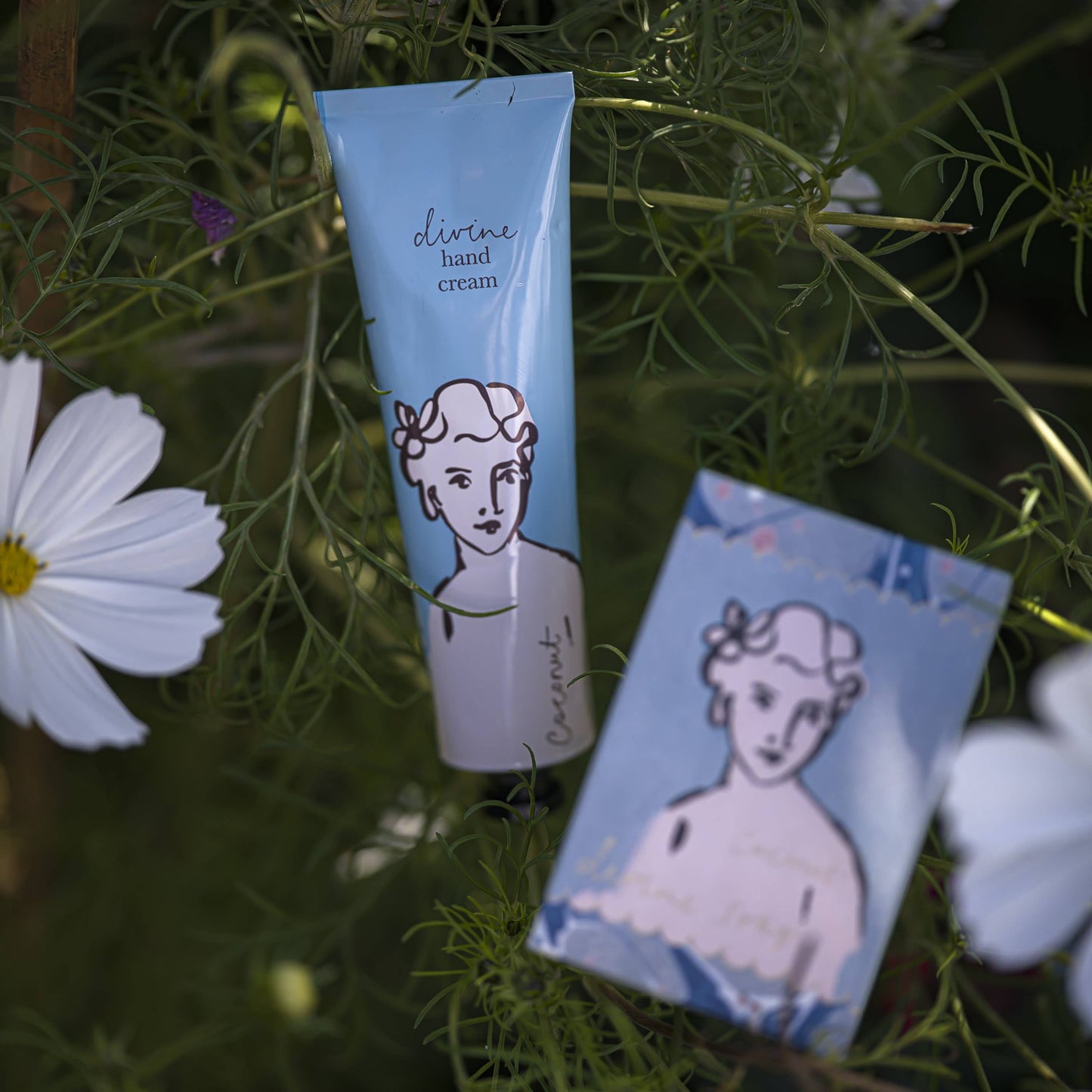 Die Archivist Gallery 'Kokosnuss' Handcreme kommt in einer blauen, veganen Tube mit einer minimalen Personendarstellung inmitten von grünem Blattwerk und weißen Blüten und bietet einen sanften Kokosnussduft. Dazu gibt es eine passende Karte oder Box mit dem gleichen Design.