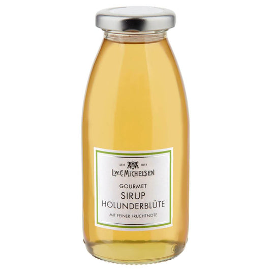 Eine durchsichtige Glasflasche mit silbernem Verschluss, gefüllt mit einer hellgelben Flüssigkeit. Auf dem Etikett steht „L.W.C. Michelsen | Gourmet-Sirup Holunderblüte 250 ml“, was darauf hinweist, dass es sich um einen hochwertigen Holunderblütensirup handelt, der von der renommierten Marke L.W.C. Michelsen für den Gourmet-Genuss hergestellt wurde.