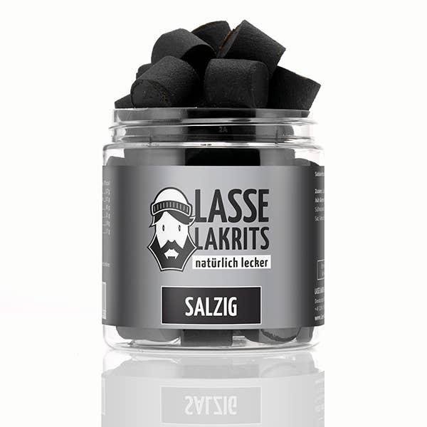 Eine durchsichtige Plastikdose mit der Aufschrift LASSE LAKRITS | Dose Lakritz Salzig natürlich lecker, auf der ein bärtiger Mann mit einem Hutlogo auf grauem Hintergrund abgebildet ist, enthält schwarze, salzige Lakritzstücke der Marke LASSE LAKRITS.