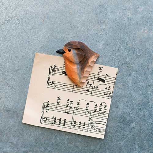 Der Wildlife Garden | 'Rotkehlchen' Magnet aus handgeschnitztem Holz zeigt ein Rotkehlchen auf Notenblatt vor grauem Hintergrund - ein charmantes Detail für Naturliebhaber.