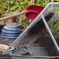 Eine rote Schaufel wirft Erde auf ein Metallgitter über einer Schubkarre während des Kurses Di., 2.3.2027 | 15.00 – 16.30 Uhr RUNDGANG: Was im März im Garten zu tun ist der Königlichen Gartenakademie.