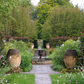 Ein von großen Terrakotta-Urnen gesäumter Steinweg führt durch den vielfältigen Garten von Yorkshire zu einem stufenförmigen Steinbrunnen, der im Rahmen des Afternoon Tea am Di., 16.2.2027 | 14.30 – 15.30 Uhr im Mittelpunkt steht.