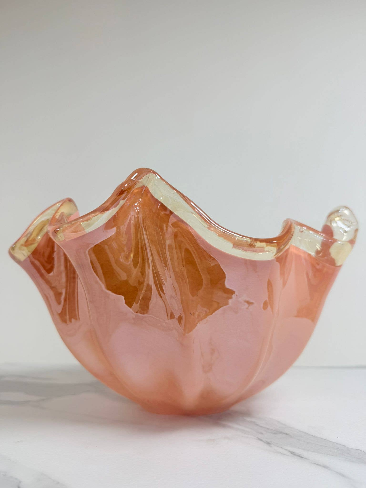 Die Murano Dream Dekoschale „Fazzoletto“ aus rosa Murano-Glas (H 20, Ø 22 cm) besticht durch ihren gewellten Rand und cremefarbene Akzente – ein elegantes Beispiel italienischer Glaskunst auf weißem Hintergrund.