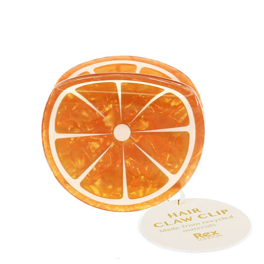 Die Rex B2B - Europe Haarklammer in Orange verfügt über ein Orangenscheiben-Design mit einer marmorierten Textur und weißen Segmentlinien, sowie einem runden Anhänger mit der Aufschrift Haarklammer. Hergestellt aus recycelten Materialien von Rex B2B - Europe.