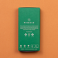 Eine grüne rechteckige Box mit der Aufschrift "Piccolo Seeds | Wildkräuter Kollektion 'Foraging Wild Herbs'" auf braunem Hintergrund. Enthält GVO-freie Wildkräuter-Samenpackungen - ideal für den Balkon. Icons zeigen Topf, Erde, Wasser; Anleitung und Website darunter.