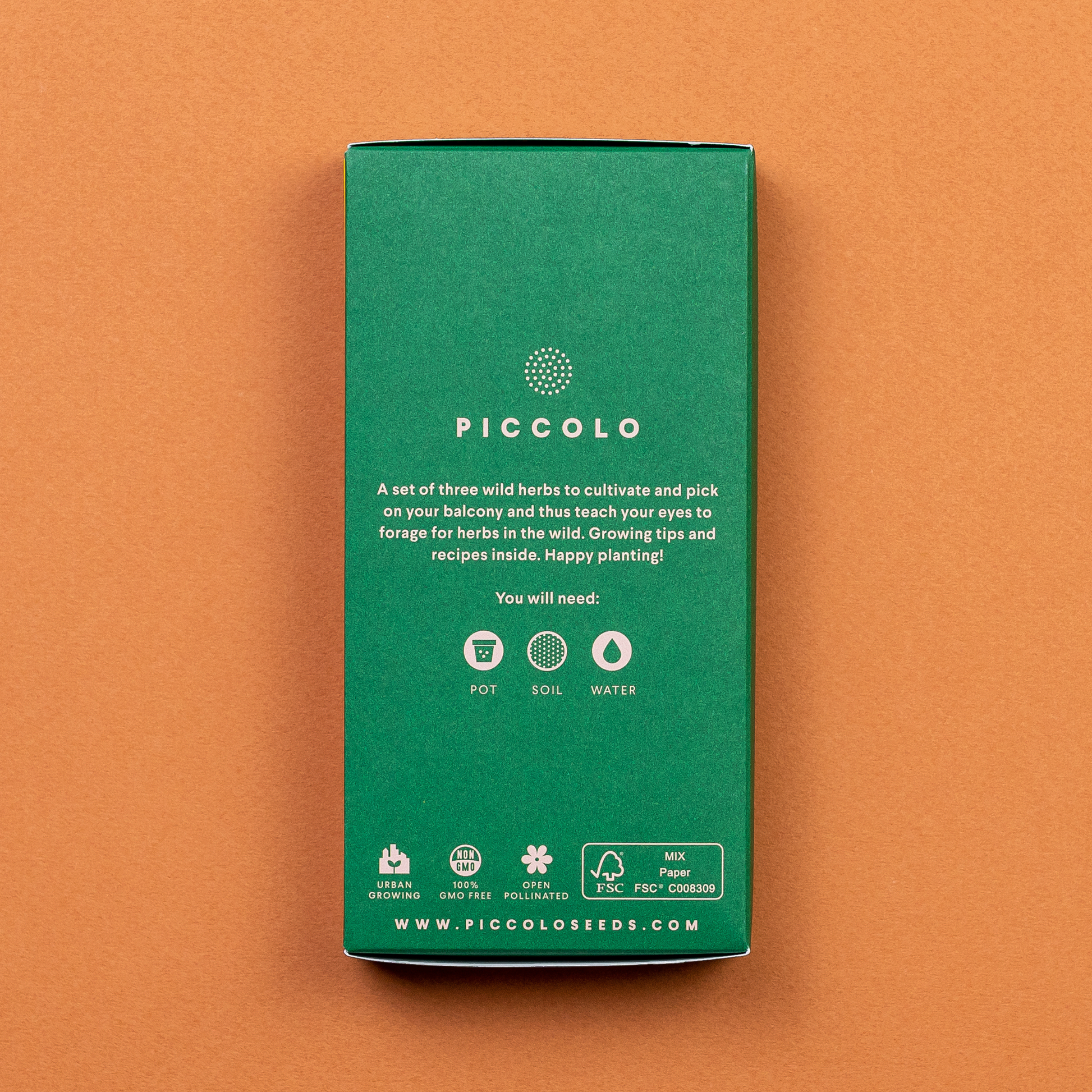 Eine grüne rechteckige Box mit der Aufschrift "Piccolo Seeds | Wildkräuter Kollektion 'Foraging Wild Herbs'" auf braunem Hintergrund. Enthält GVO-freie Wildkräuter-Samenpackungen - ideal für den Balkon. Icons zeigen Topf, Erde, Wasser; Anleitung und Website darunter.