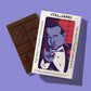 Eine 'Padrino' Bio-Schokolade mit Karamell und Salz von I AM ITALIANO, verziert mit italienischen Handgesten, liegt neben der Box. Auf der Verpackung stehen "I AM ITALIANO" und "The Most Italian Chocolate".