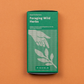Eine grüne Packung mit der Aufschrift Piccolo Seeds | Wildkräuter Kollektion "Foraging Wild Herbs" zeigt eine Hand, die nach Blättern greift, auf orangem Hintergrund. Ideal für Balkons, listet es verschiedene Kräuter auf und ist garantiert gentechnikfrei. Marke: Piccolo Seeds.