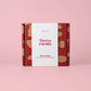 Auf einem rosa Hintergrund steht eine aufrecht stehende rot-beige Schachtel mit einem weißen Etikett, auf dem „Alfar Tierra Cocida | Kleine Keramik Knoblauchreibe ‚Pomodoro‘“ zu lesen ist. Die Verpackung zeigt Illustrationen von beigen Küchenutensilien und unterstreicht damit die traditionelle Keramikkunst dieser handgefertigten spanischen Knoblauchreibe von Alfar Tierra Cocida.
