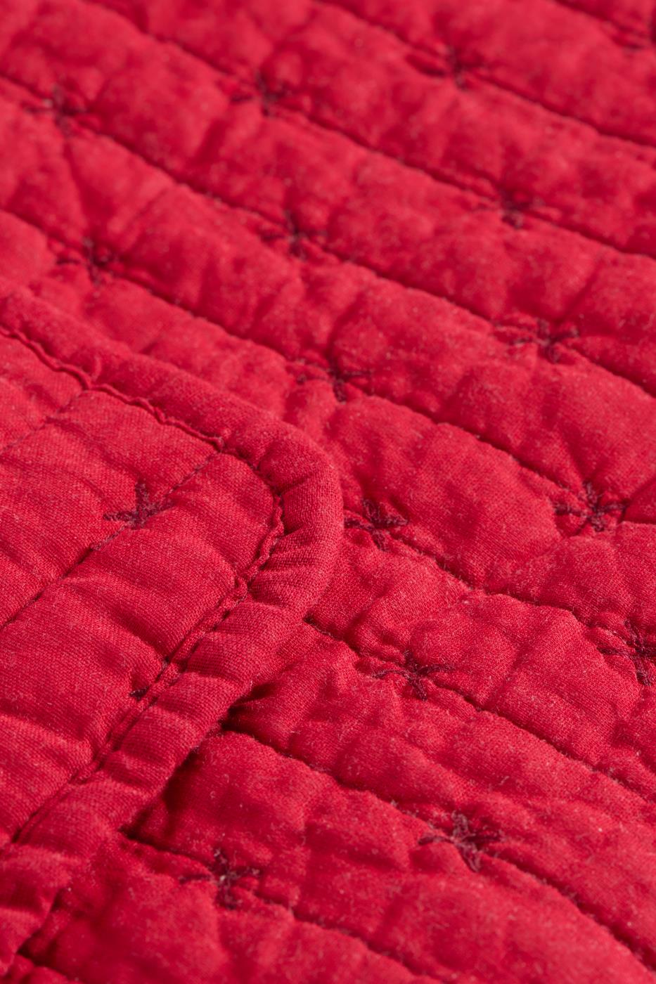 Die Nahaufnahme der IB Laursen Quilt Decke rot mit Kreuzstich zeigt den roten Steppstoff mit Gitter- und Kreuzstichdetails sowie eine gefaltete Kante, die den typischen Ib Laursen-Stil widerspiegelt.
