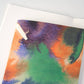 Das Papaya Paper Products | Notizheft A6 mit Aquarell/Watercolor-Motiv hat leere Seiten und einen FSC-zertifizierten abstrakten Einband in Grün, Orange, Lila und Blau. Es ruht auf einer weißen Oberfläche, ideal für nachhaltige Notizen.