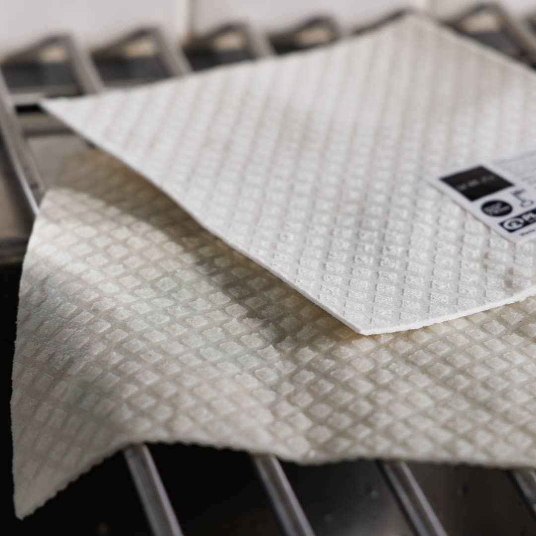 Zwei 'Rote Tulpen' Schwammtücher von More Joy Home liegen auf einem Metalltrockner, eines überlappt das andere. Das Label ist sichtbar. Die Tücher sind biologisch abbaubar - ideal als Zero-Waste-Produkt.