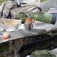 Auf einem rustikalen Picknicktisch mit Decke, Bratpfanne, Apfel und Tasche gießt jemand ein Heißgetränk aus einer grünen Thermoskanne in die Sagaform GmbH Kaffeebecher terrakotta (2-teilig) in einladender Outdoor-Atmosphäre.
