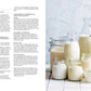 Eine Auswahl von Speisekammer-Glasflaschen und -Gläsern aus dem Hölker Verlag, gefüllt mit Milch und Joghurt, arrangiert auf einer weißen Fläche neben einer aufgeschlagenen Kochbuchseite mit deutschen Joghurt-Rezepten - ideal für Liebhaber selbstgemachter Speisen.