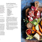 Blick von oben auf rohe Rinderknochen, Gemüse, Gewürze und Rotwein auf einem rustikalen Tisch neben dem deutschen Rezeptbuch Speisekammer des Hölker Verlags - ideal für selbstgemachte Gerichte.