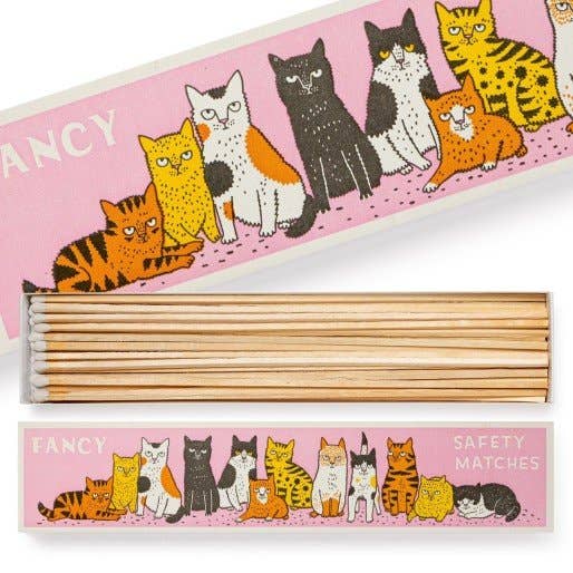 Die 'Fancy Cat' langen Sicherheitsstreichhölzer von Archivist Gallery kommen in einer rechteckigen Schachtel mit einem rosa Deckel, auf dem bunte Katzen abgebildet sind. Im Inneren kommen beim Öffnen die ordentlich angeordneten langen Streichhölzer zum Vorschein.