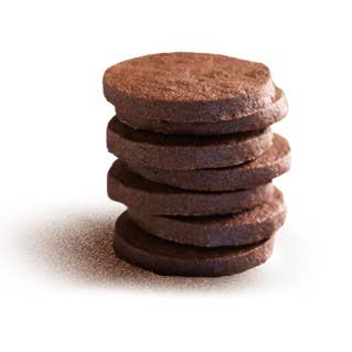 Ein Stapel von fünf runden Lady Joseph Butterkekse und Schokolade Dunkle Schoko-Shortbread Kekse ist auf einem weißen Hintergrund angeordnet, mit Krümeln am Boden verstreut.