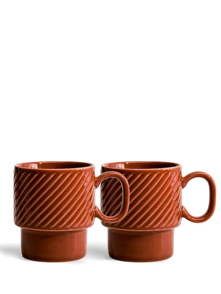 Zwei terrakottafarbene Sagaform Kaffeebecher der Sagaform GmbH, die als 2-teiliges Set verkauft werden, zeichnen sich durch diagonale Strukturmuster, große Griffe und ein modernes geometrisches Design aus. Sie sind nebeneinander auf einem weißen Hintergrund abgebildet.