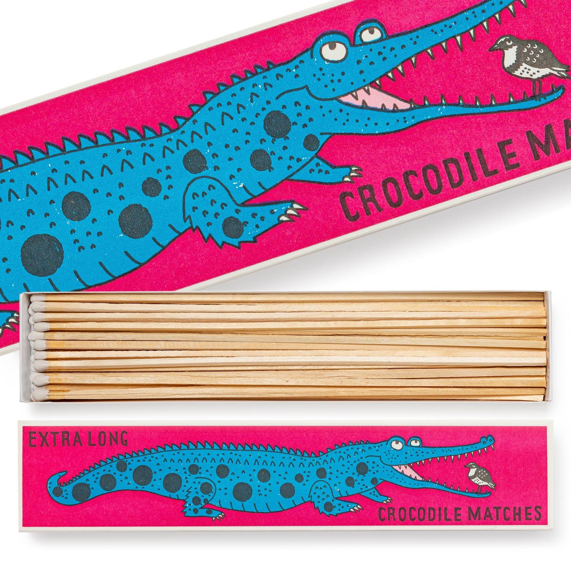 Die "Krokodil" Extra lange Streichhölzer von Archivist Gallery kommen in einer leuchtend rosa Schachtel mit einem blauen Cartoon-Krokodil und einem kleinen Vogel. Auf dem verspielten Design stehen die Worte "Krokodil Streichhölzer" und "Extra lang".
