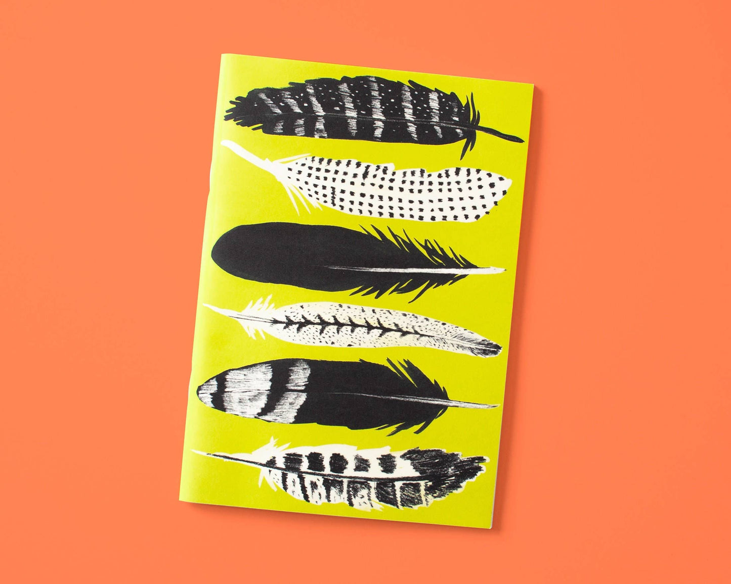 Papaya Paper Products | Schönes Notizheft A5 mit Federn in gelb: Dieses Notizheft besticht durch sechs schwarz-weiße Federillustrationen auf gelbem Cover, orange hinterlegt. Aus FSC-zertifiziertem Munken Print Cream Papier für ein hochwertiges Schreibgefühl.