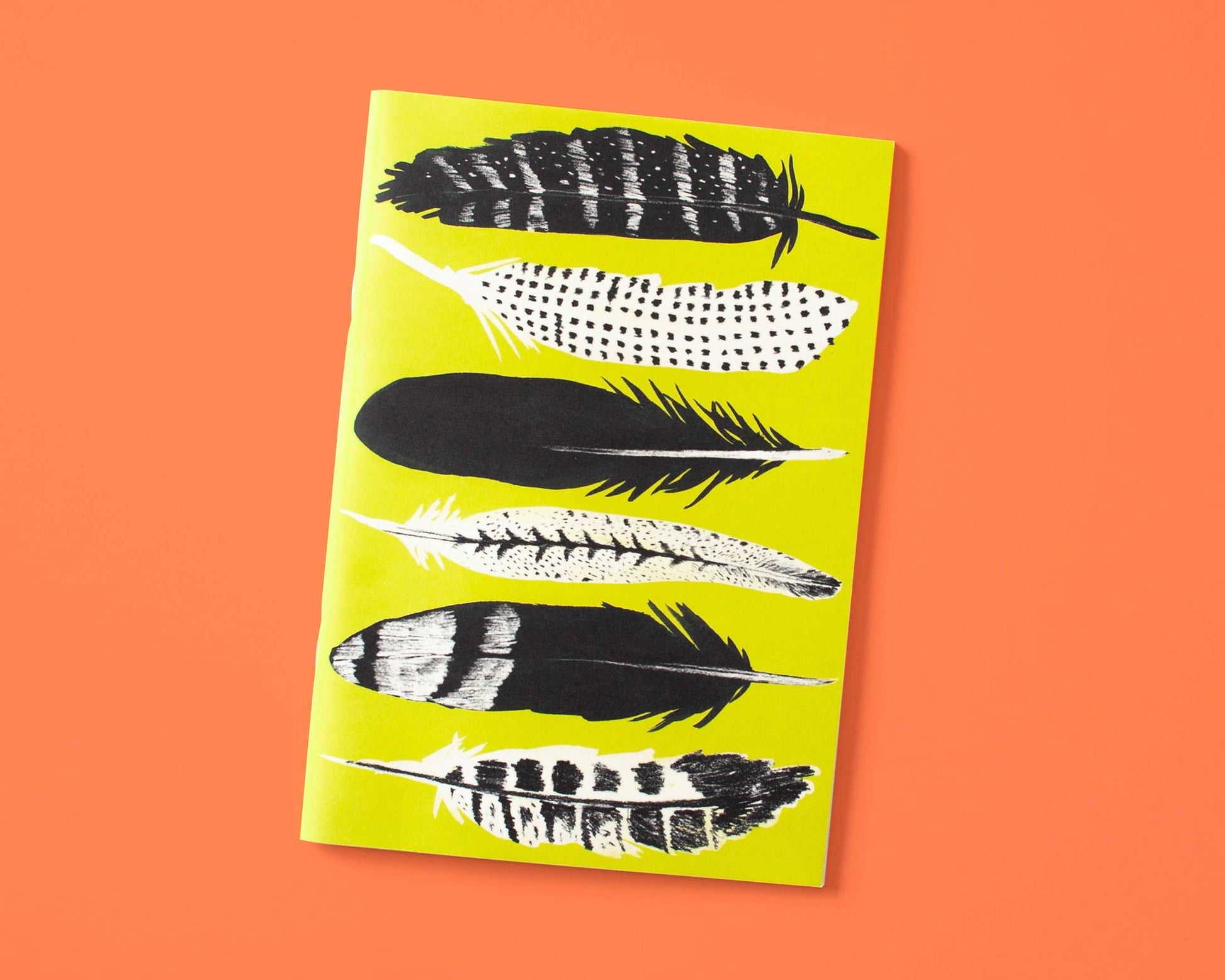 Papaya Paper Products | Schönes Notizheft A5 mit Federn in gelb: Dieses Notizheft besticht durch sechs schwarz-weiße Federillustrationen auf gelbem Cover, orange hinterlegt. Aus FSC-zertifiziertem Munken Print Cream Papier für ein hochwertiges Schreibgefühl.