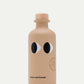 Eine beigefarbene Keramikflasche mit einem Holzdeckel, zwei Cartoon-Augen und dem Aufdruck "yiayia and friends" am Boden sowie einem runden Etikett für Yiayia and friends | Natives Olivenöl Extra mit Knoblauch 200 ml. Abgebildet auf einfarbig weißem Hintergrund.