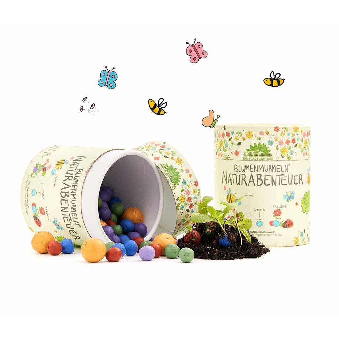 Zwei verzierte Behälter, von denen einer umgekippt ist und bunte „Stadtgärtner“-Samen | Blumenmurmeln „Naturabenteuer“ aus der 100er-Dose, mit einigen oben abgebildeten Schmetterlingen und Bienen sowie einer kleinen Pflanze, die aus der Erde und den Saatkugeln in der Nähe der Behälter wächst – perfekt als nachhaltiges Geschenk für Kinder und ein spannendes Naturabenteuer für Kinder.