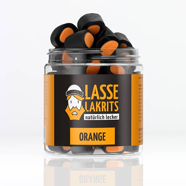 Ein durchsichtiges Plastikgefäß mit der Aufschrift LASSE LAKRITS | Dose Lakritz Orange enthält fruchtige Lakritze in Schwarz und Orange, mit einer Illustration eines bärtigen Mannes mit Mütze, plakativem Schriftzug sowie "ohne Palmöl" und "natürlich lecker ORANGE" auf dem Etikett.