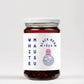 Ein Glas „White Mausu | Black Bean Rayu Sauce“ von White Mausu Ltd mit einem minimalistischen weißen Etikett mit blauem und rosa Text sowie einer runden Maus-Illustration. Darin befindet sich eine dunkle, stückige, scharfe Sauce aus chinesischen schwarzen Bohnen, die für zusätzliche Geschmackstiefe sorgt.