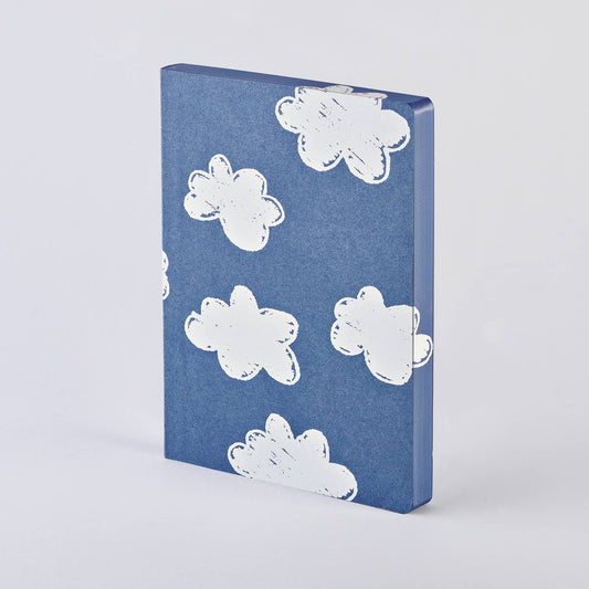 Das nuuna | „Head In The Clouds“ Notizbuch Graphic L A5+ von nuuna steht aufrecht vor einem schlichten, hellen Hintergrund und präsentiert seinen blauen, matten Einband, der mit weißen Wolkenillustrationen im handgezeichneten Stil verziert ist. Dieses Notizbuch wurde fachmännisch aus recyceltem Denim und Premium-Papier gefertigt und verbindet Nachhaltigkeit mit einzigartigem Design.