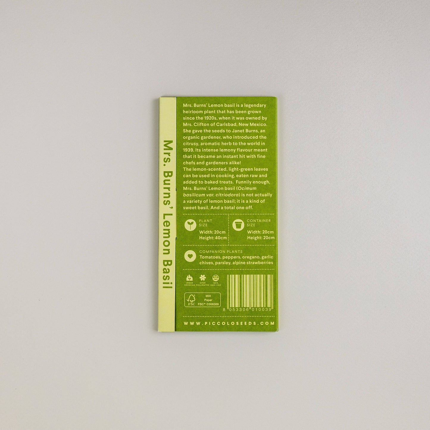 Eine grüne Piccolo Seeds-Packung mit der Aufschrift "Basilikum Mrs. Burns Zitrone" steht aufrecht auf einer hellen Fläche und zeigt Pflanzanweisungen, Symbole und eine Beschreibung dieses aromatischen Krauts und der geschätzten Erbstückpflanze.